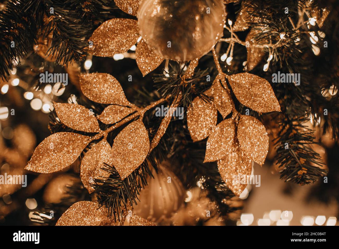 Composition de Noël étincelante avec feuilles dorées scintillantes accrochées à l'arbre de Noël.Décoration festive du nouvel an Banque D'Images