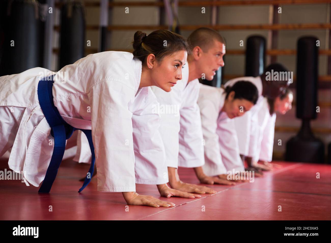 Groupe multiracial d'hommes et de femmes qui font des push-up dans la salle de gym Banque D'Images