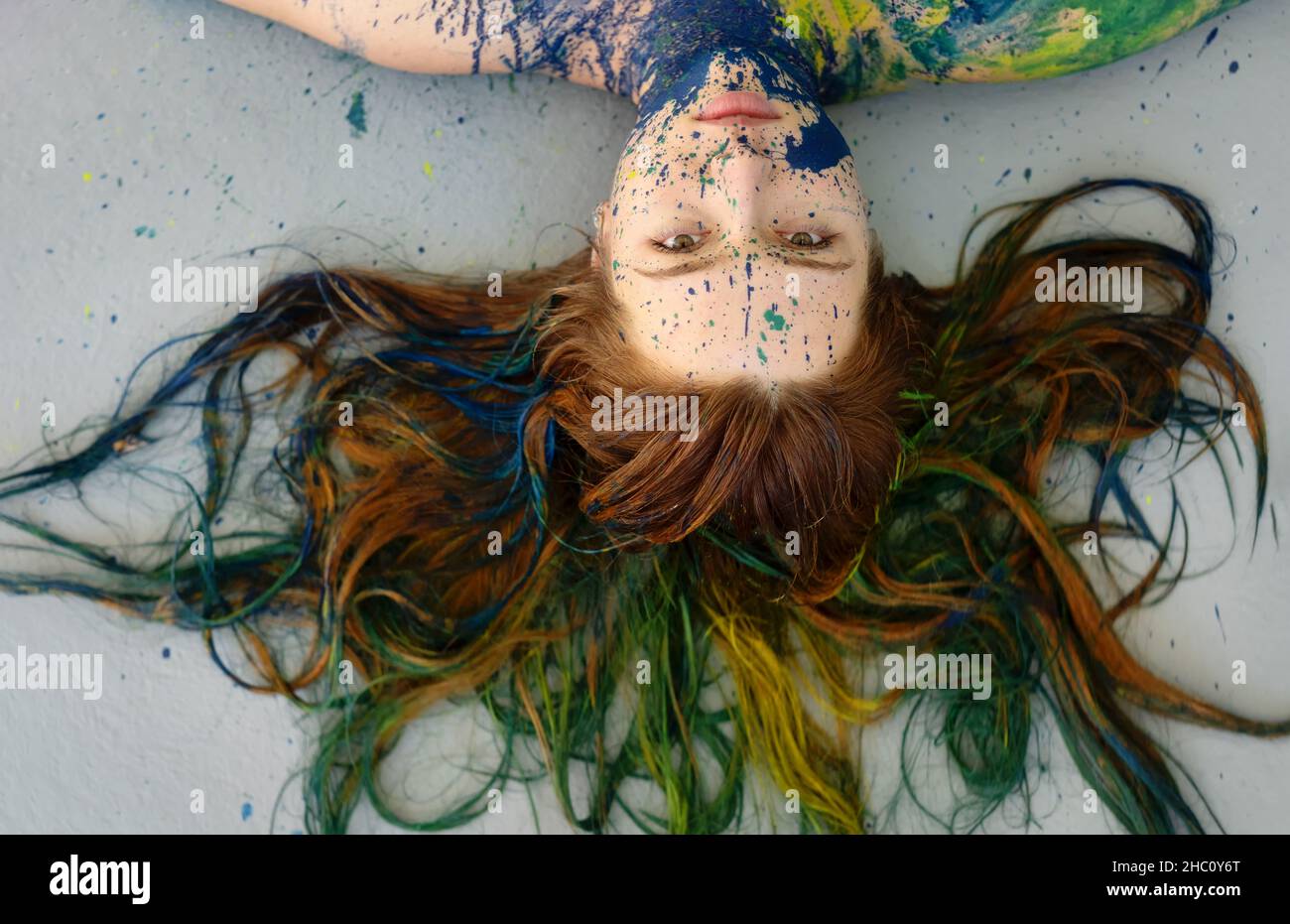 remarquable inhabituel portrait impressionnant d'une jeune femme brunette à tête rouge à poil long, points de peinture bleue et verte, expressiv créatif décoratif Banque D'Images