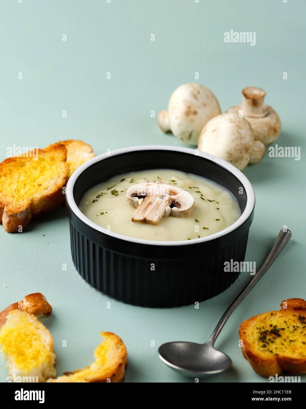 Soupe crémeuse aux champignons avec baguette de pain à l'ail croustillant, servir sur un bol en céramique noire ou sur le ramaquin Banque D'Images