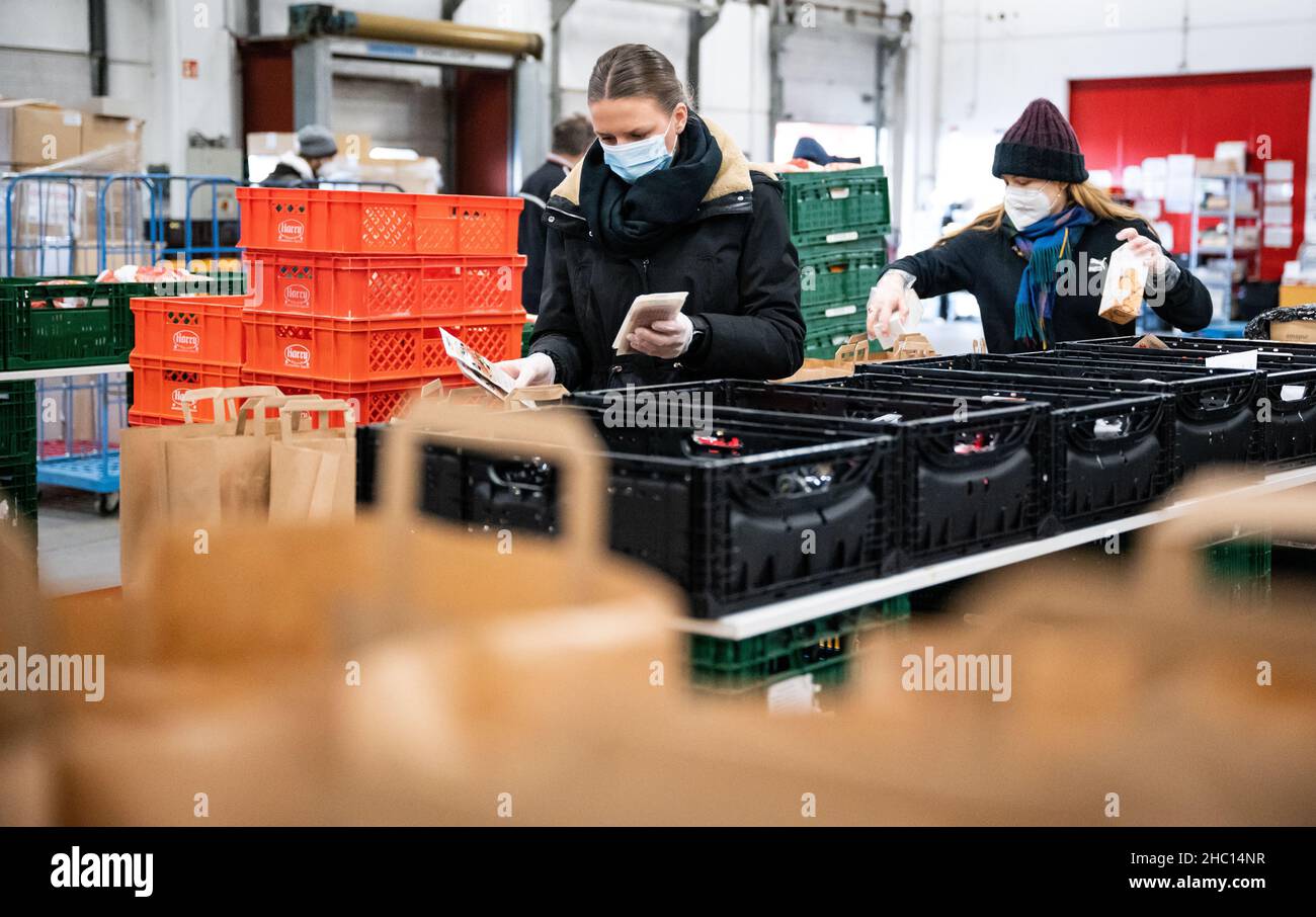 22 décembre 2021, Berlin: Celina Räder (l) et Amelie Tempel placent la nourriture dans des sacs en papier dans une salle du Berliner Tafel sur le marché de gros de Berlin.Actuellement, près de 40 000 aides emballez chaque jour plus de 1 000 colis de Noël pour les nécessiteux et les sans-abri.Environ 8 000 de ces sacs bien remplis sont distribués par les institutions sociales pendant la saison de Noël.Mais : par rapport aux années précédentes, le Tafel de Berliner souffre d'un énorme déclin des dons alimentaires.Les grandes chaînes de vente au détail vendent maintenant jusqu'à 99 % de leur nourriture.Cela laisse moins pour les nécessiteux.(À dpa 'Tafel reçoit moins de dons Banque D'Images