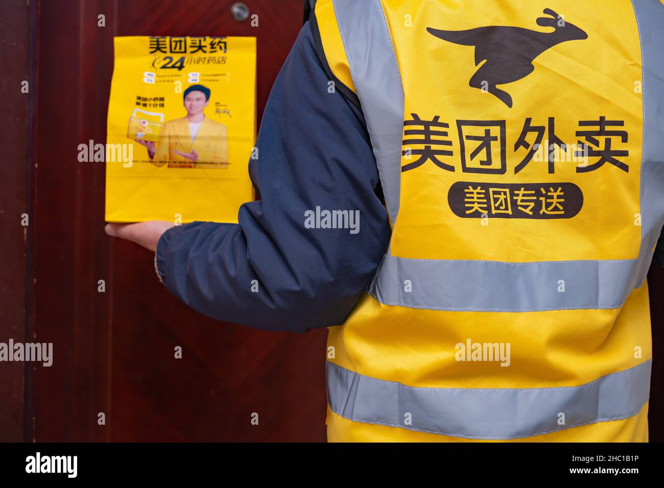 Zhongshan,Chine-décembre 22, 2021:homme livrant un pack de Meituan avec des médicaments à la maison des clients. Banque D'Images