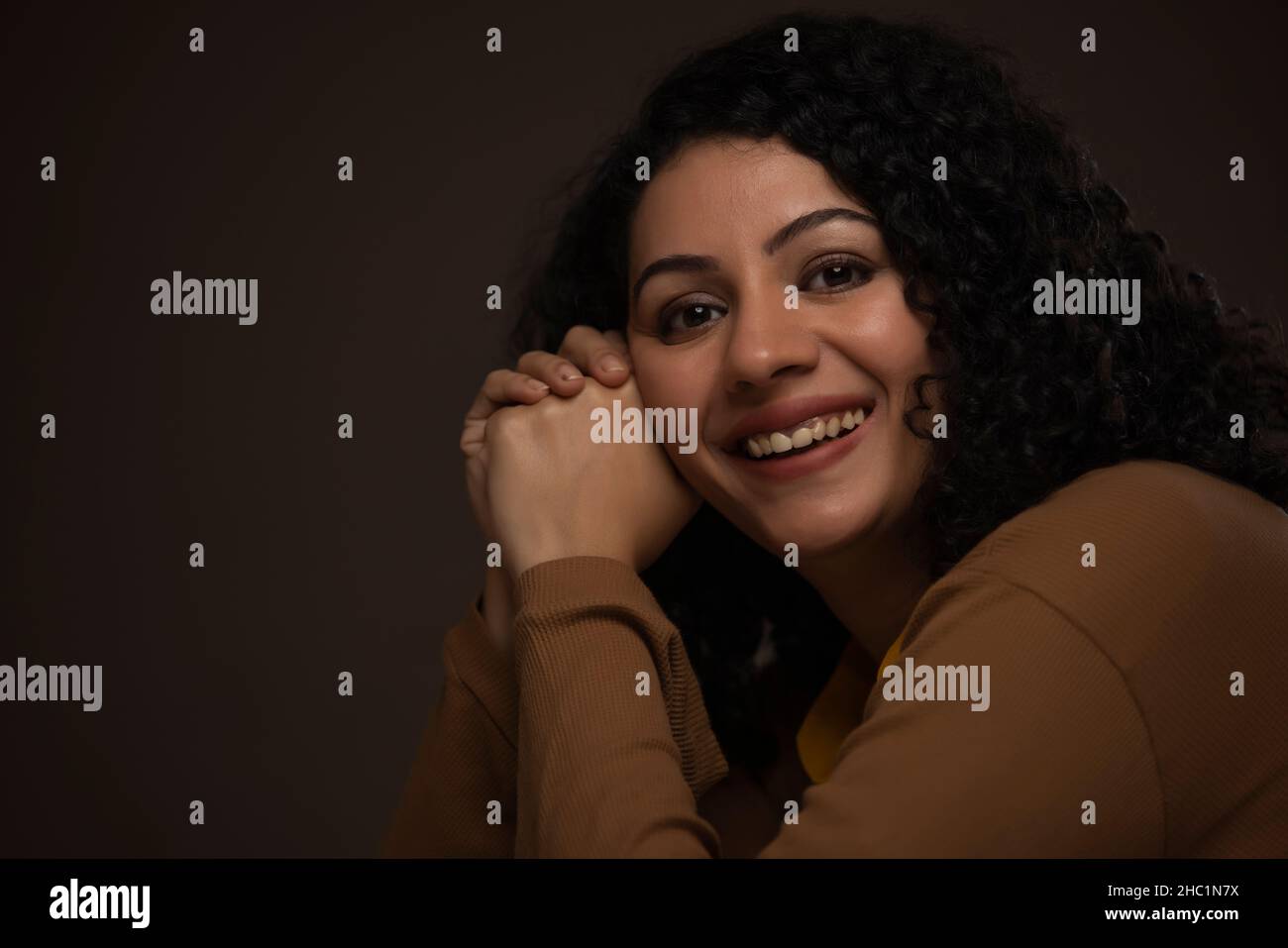 Vue latérale d'une femme souriante regardant l'appareil photo Banque D'Images