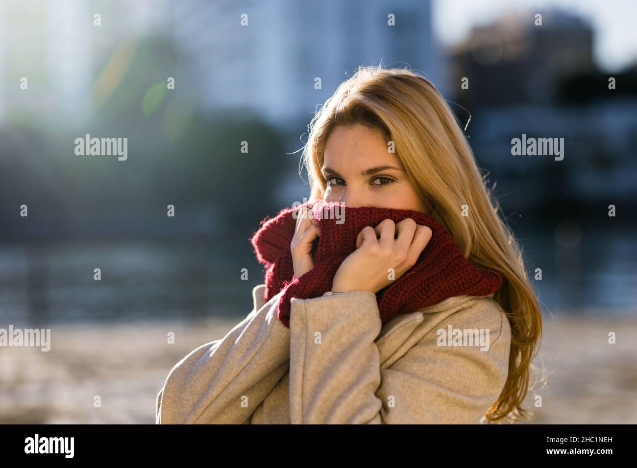 Une jeune fille adolescente regarde au-dessus du foulard rouge dans la ville au coucher du soleil. Banque D'Images