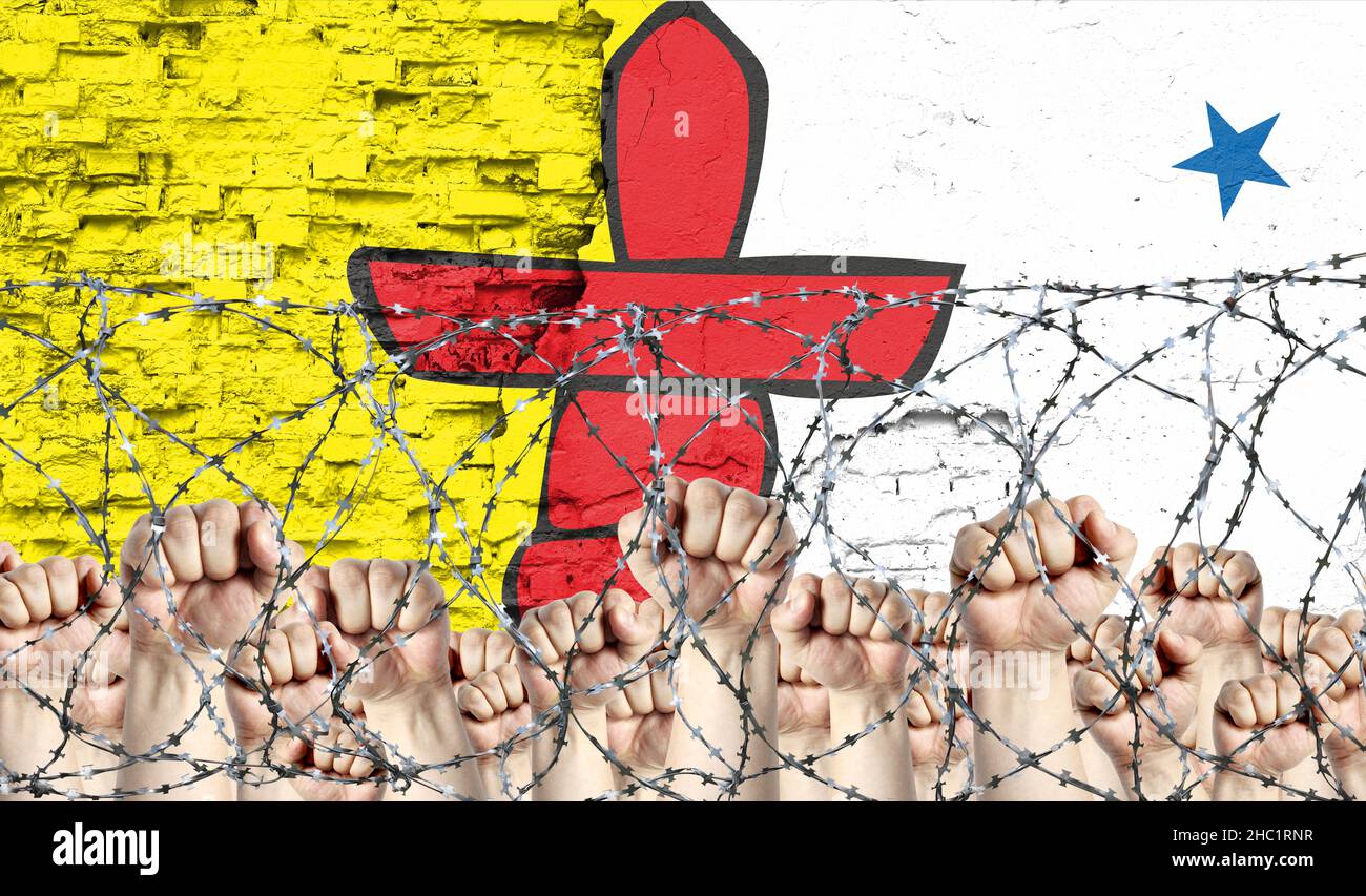 Barbelés contre le fond du drapeau infligé du Nunavut et des poings levés Banque D'Images