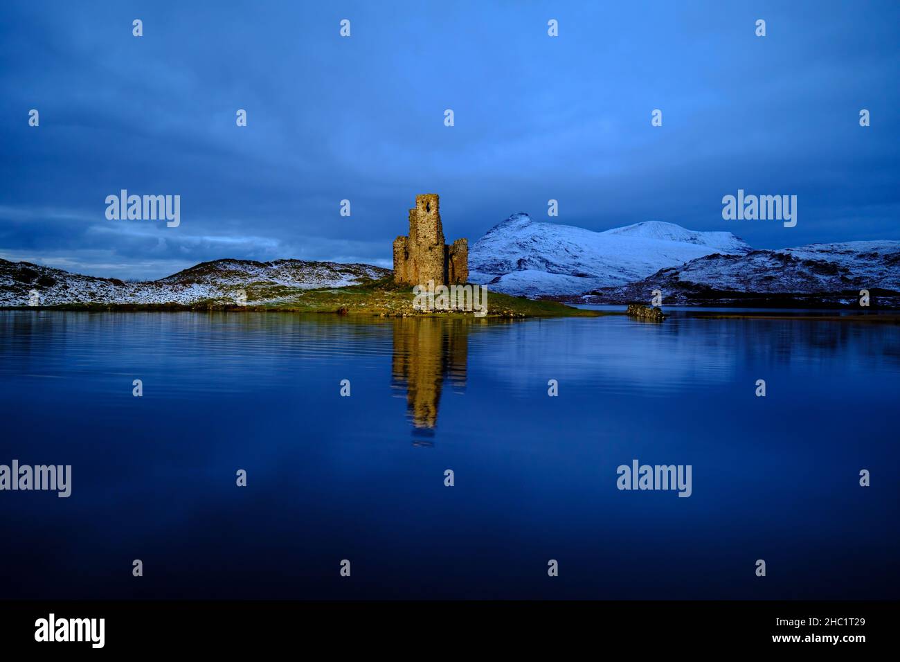 Le château Ardvreck datant de 16th ans, sur le Loch Assynt, à Sutherland, en Écosse, est artificiellement éclairé après le coucher du soleil. Banque D'Images