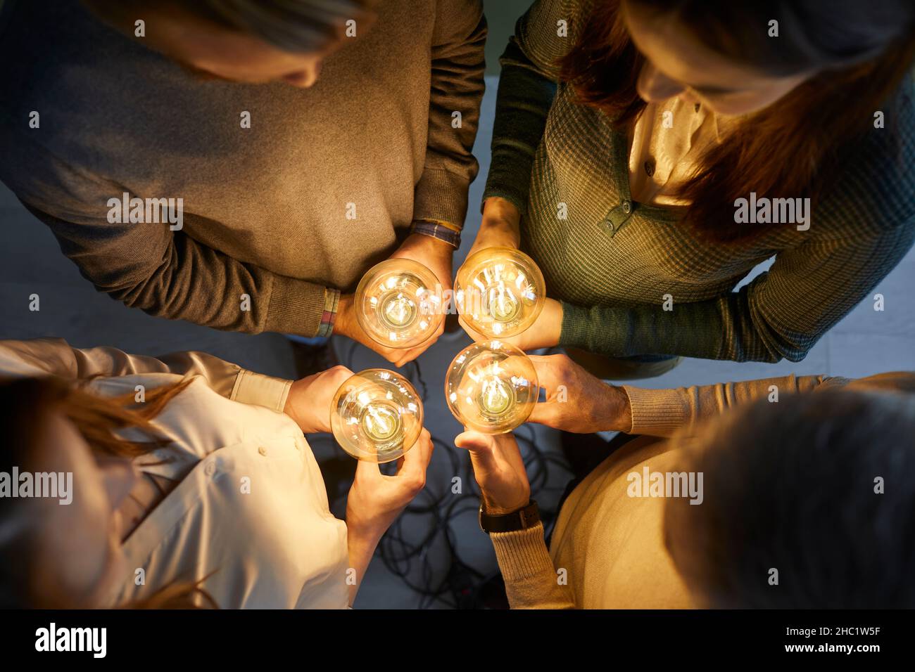 Équipe de personnes tenant des ampoules électriques illustrant le concept de l'idée créative et de l'innovation Banque D'Images
