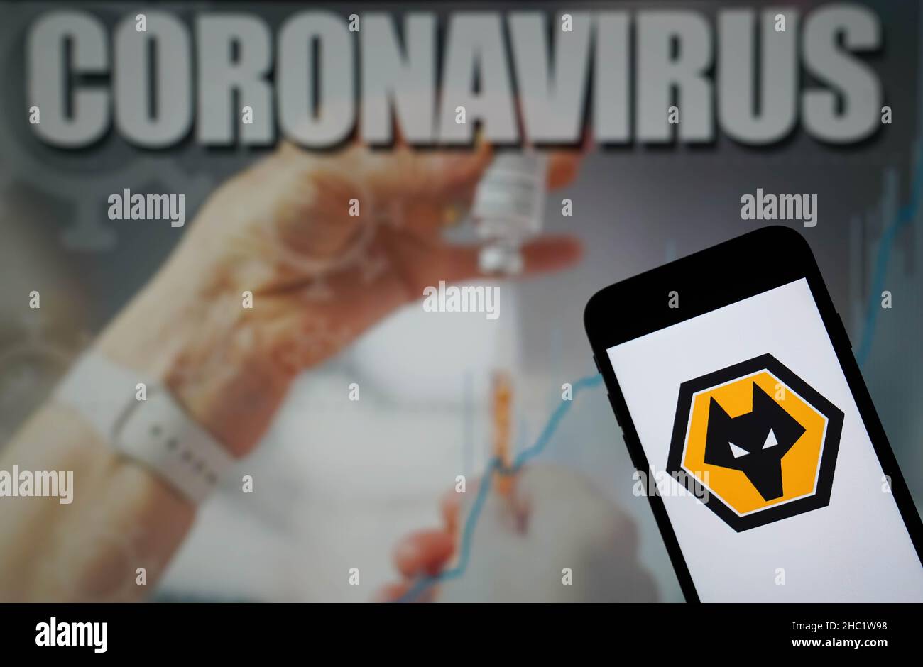 Photo du dossier datée du 09-01-2021 du logo Wolverhampton Wanderers football Club affiché sur un téléphone portable avec une illustration du coronavirus sur un moniteur en arrière-plan.Le match de Liverpool contre Leeds et le match de Wolves contre Watford le lendemain de Noël ont été mis fin à cause d’infections à coronavirus, a annoncé la Premier League.Date d'émission : jeudi 23 décembre 2021. Banque D'Images