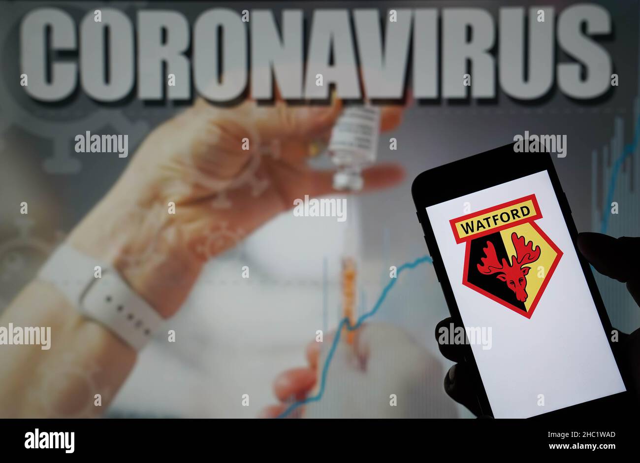 Photo du dossier datée du 09-01-2021 du logo du Watford football Club affiché sur un téléphone portable avec une illustration du coronavirus sur un moniteur en arrière-plan.Le match de Liverpool contre Leeds et le match de Wolves contre Watford le lendemain de Noël ont été mis fin à cause d’infections à coronavirus, a annoncé la Premier League.Date d'émission : jeudi 23 décembre 2021. Banque D'Images