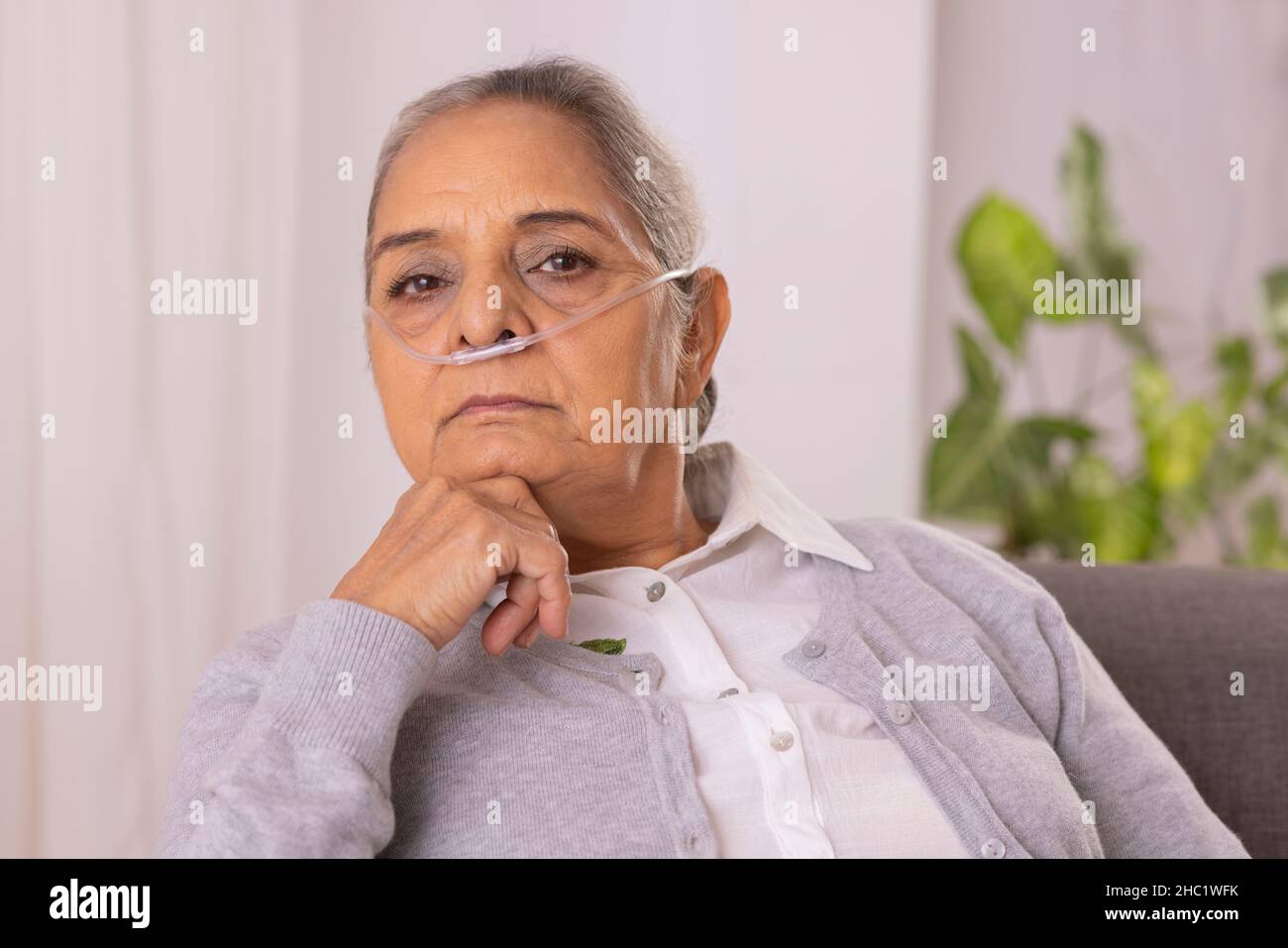 Vieille femme assise sur un canapé avec canule nasale à la maison Banque D'Images