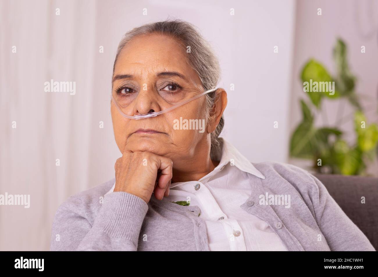 Vieille femme assise sur un canapé avec canule nasale à la maison Banque D'Images