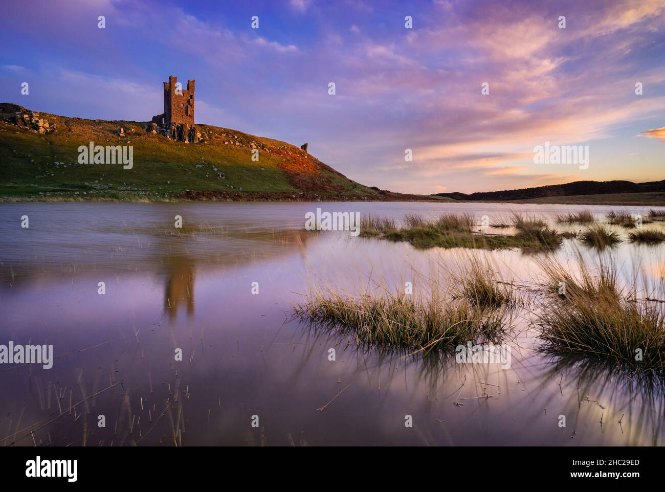 Château de Dunstanburgh réflexions au coucher du soleil Embleton Bay Dunstanborough Northumberland Coast Angleterre GB Royaume-Uni Europe Banque D'Images