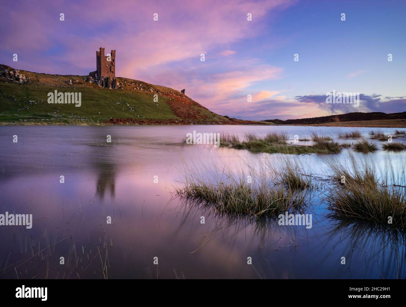 Château de Dunstanburgh Northumberland Angleterre se reflète dans un bassin d'eau de mer Embleton Bay Northumberland côte Angleterre GB Royaume-Uni Europe Banque D'Images