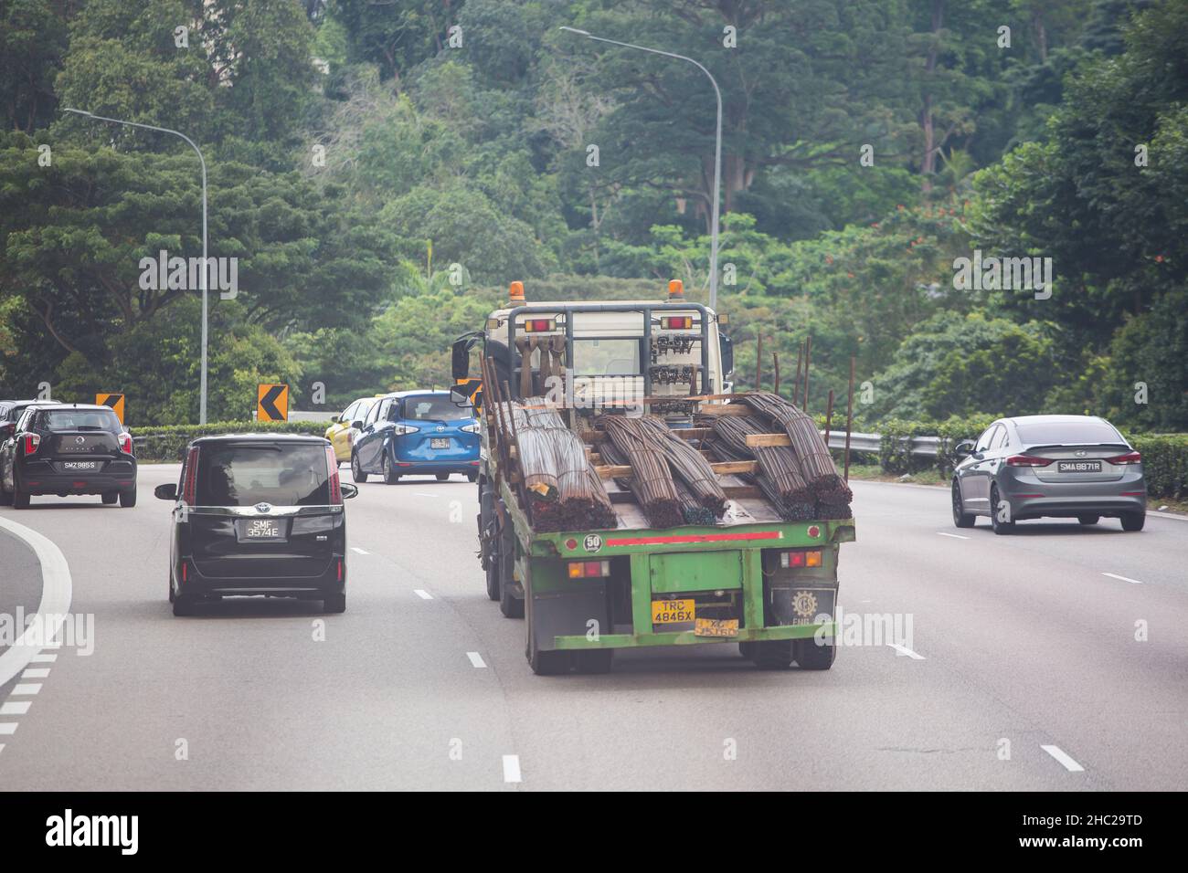 Un camion-remorque qui se déplace sur la route transporte de longs aciers sur la route jusqu'à la prochaine destination de déchargement. Singapour. Banque D'Images