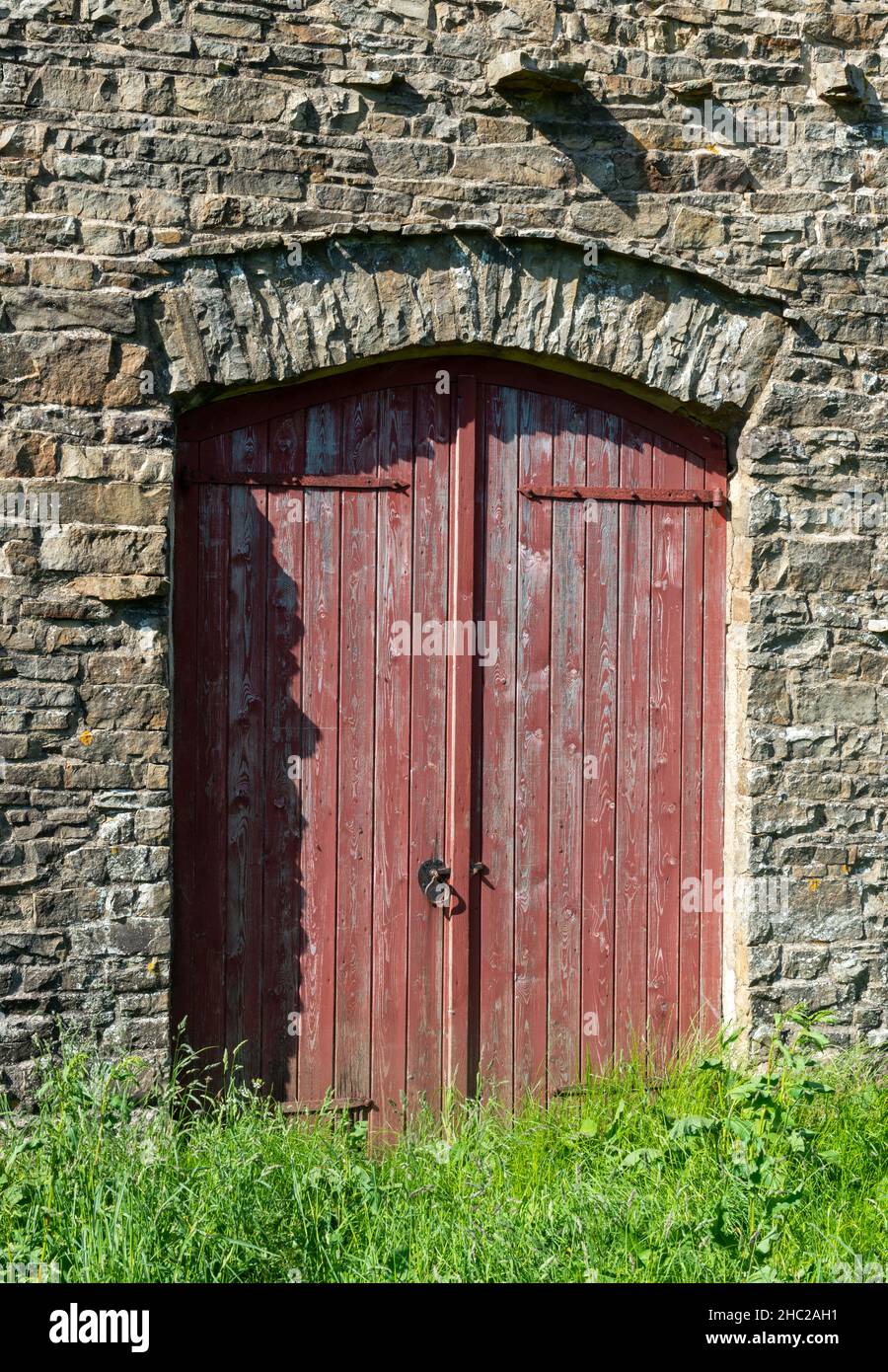 Des portes peintes en rouge forment l'entrée d'une grange traditionnelle construite sur des estons dans les Yorkshire Dales Banque D'Images