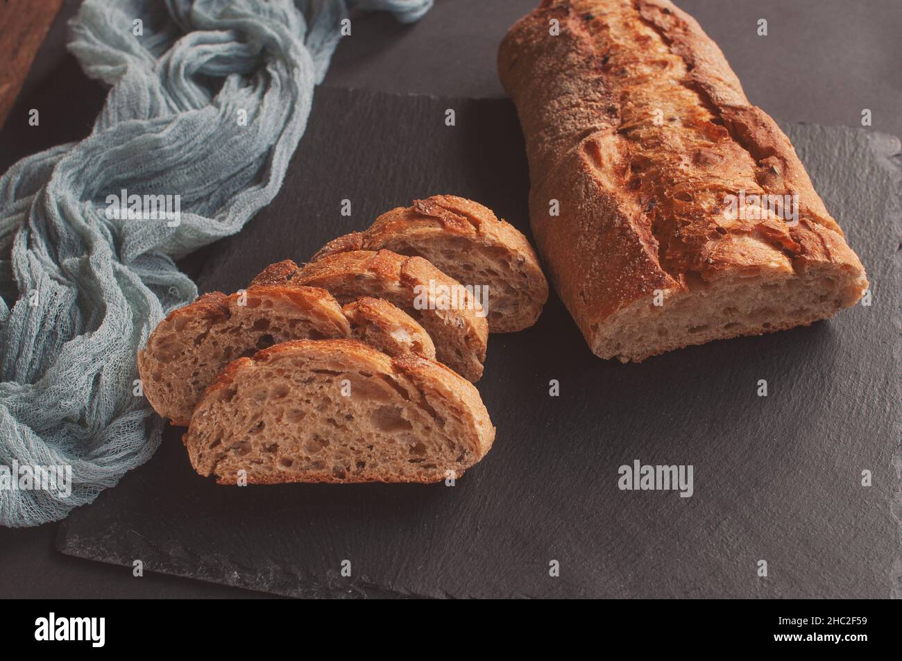 Baguette de sélection de pain à la main avec nappe de gaze grise sur fond noir Banque D'Images