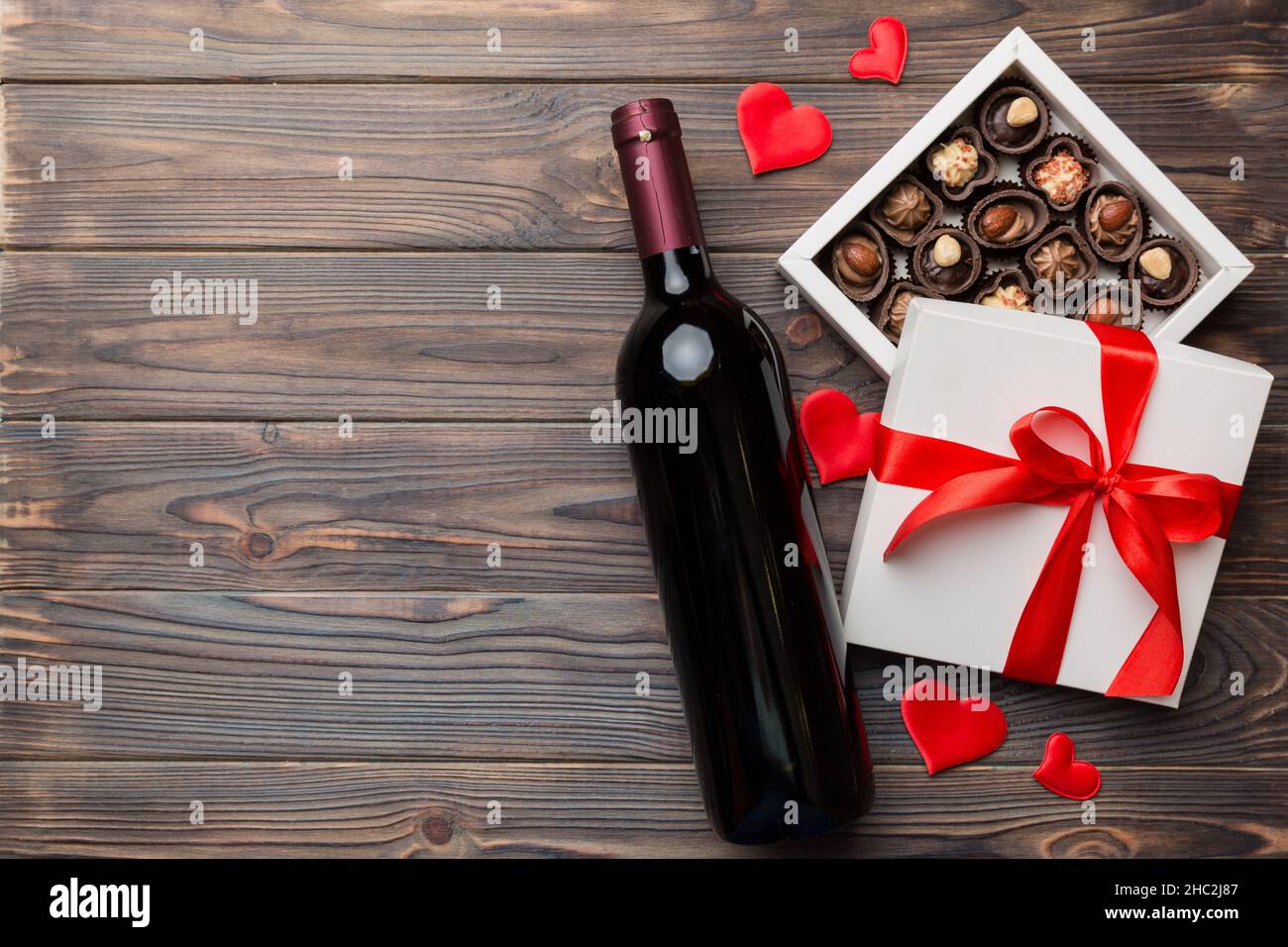Bouteille de vin rouge sur fond coloré pour la Saint-Valentin avec cadeau  et chocolat.En forme de coeur avec boîte cadeau de chocolats, vue sur le  dessus avec espace pour les copies Photo