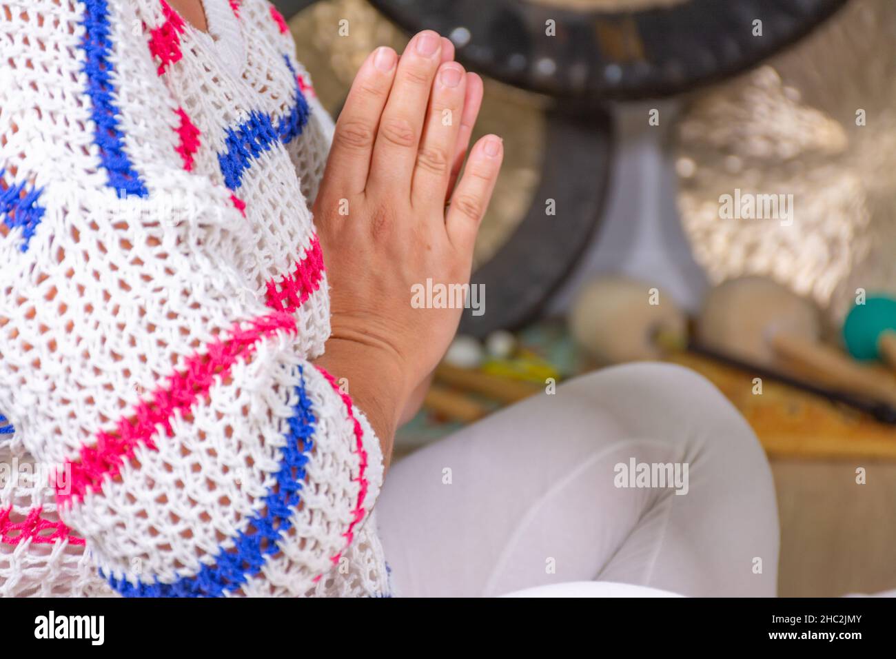 Femme vêtue de blanc pratiquant le yoga kundalini assis sur le sol et les mains ensemble Banque D'Images