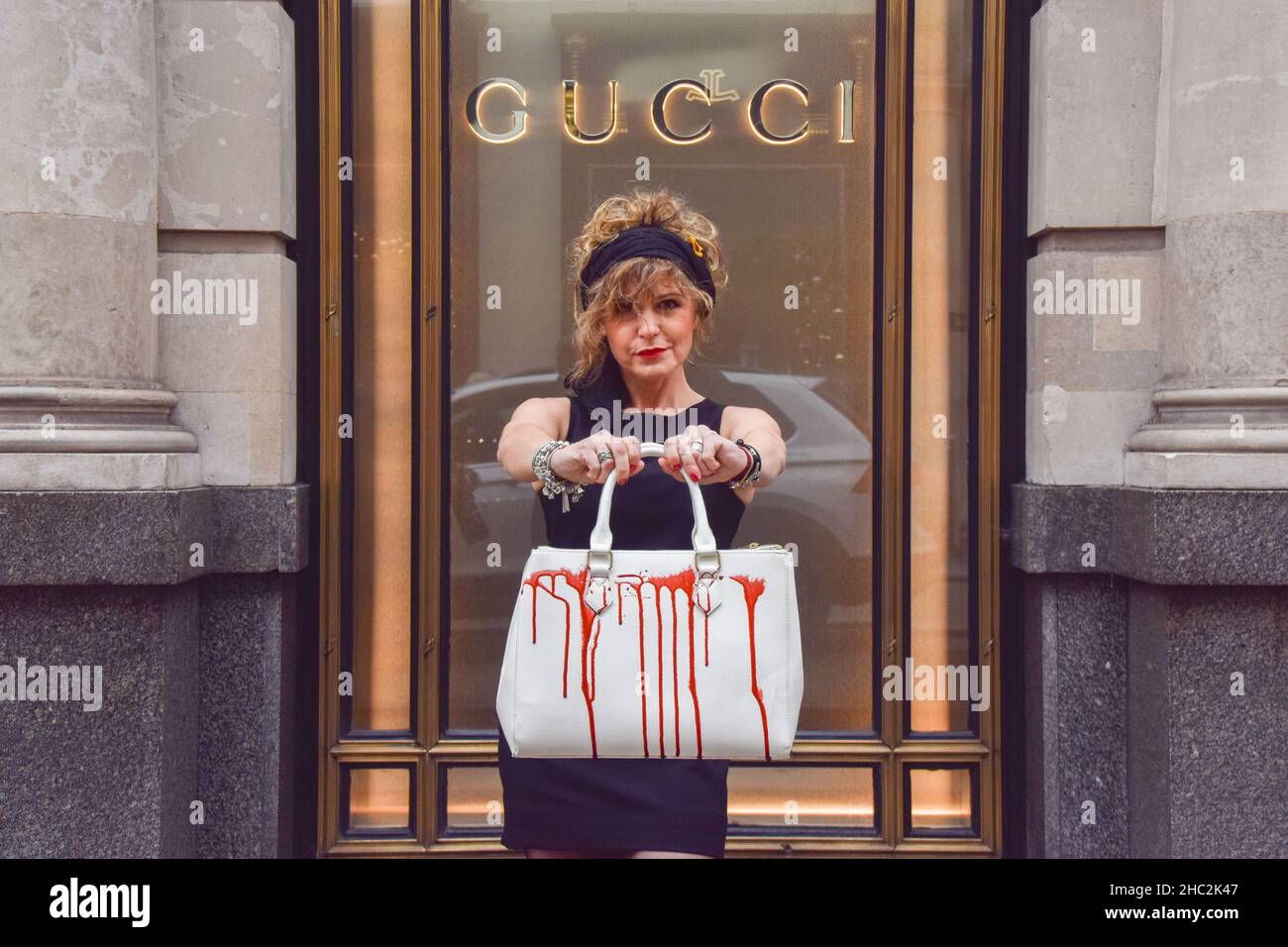 Un activiste tient un sac à main écrasé de faux sang pendant la manifestation.des militants du PETA (People for the Ethical Treatment of Animals) se sont rassemblés devant le magasin Gucci de Bond Street et ont organisé une passerelle avec des sacs à main éclaboussés de faux sang pour protester contre l'utilisation de peaux de lézard dans les produits de Gucci.L'enquête de PETA a montré que les fournisseurs de peau de lézard tombent bien en dessous des normes de bien-être des animaux et causent d'énormes souffrances pour les animaux. Banque D'Images