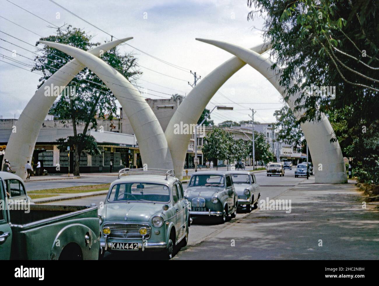 Les défenses de Mombasa (ou Mapemba ya Ndovu ou Pembe za Ndovu € le Swahili pour les défenses d'éléphant), un monument sur l'avenue moi, Mombasa, Kenya photographié en 1967.Construit en 1952 pour commémorer la visite de la famille royale britannique, l'arche comprenait à l'origine deux structures de tusk en bois et en toile.Lorsque la route a été élargie en deux voies, un nouvel ensemble de quatre défenses en aluminium résistant aux intempéries a été construit en 1956 par le conseil municipal.Ils ont ensuite formé la lettre «M».Cette image provient d'une ancienne transparence couleur Kodak 35mm amateur, une photographie vintage 1960s. Banque D'Images