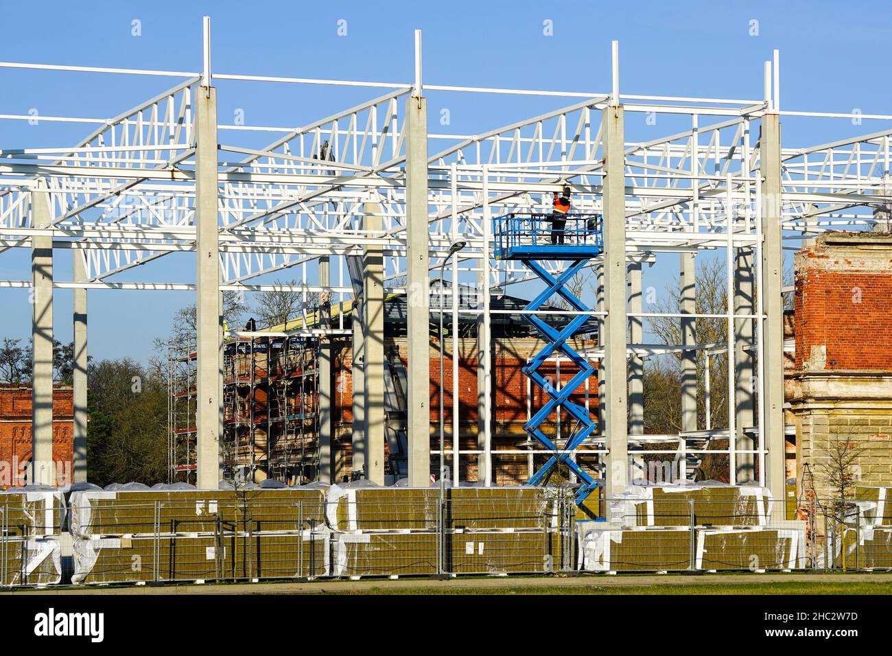 travailleur en équipement de protection uniforme et de sécurité sur un chariot automoteur lors de l'installation et de l'assemblage des cadres de construction métalliques Banque D'Images