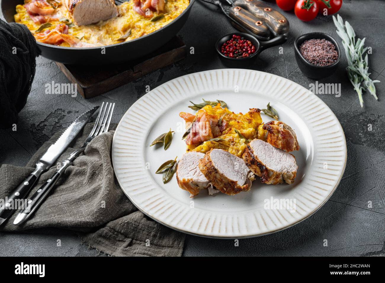 Filet de porc grillé et gratin de pommes de terre avec sauge et prosciutto, sur plat, sur fond de pierre grise Banque D'Images