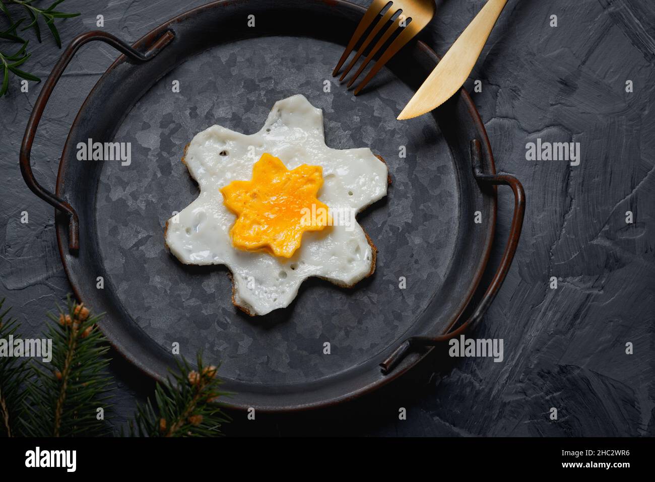 Œuf frit fait maison dans une poêle d'époque sur fond gris.Jaune en forme d'étoile. Banque D'Images