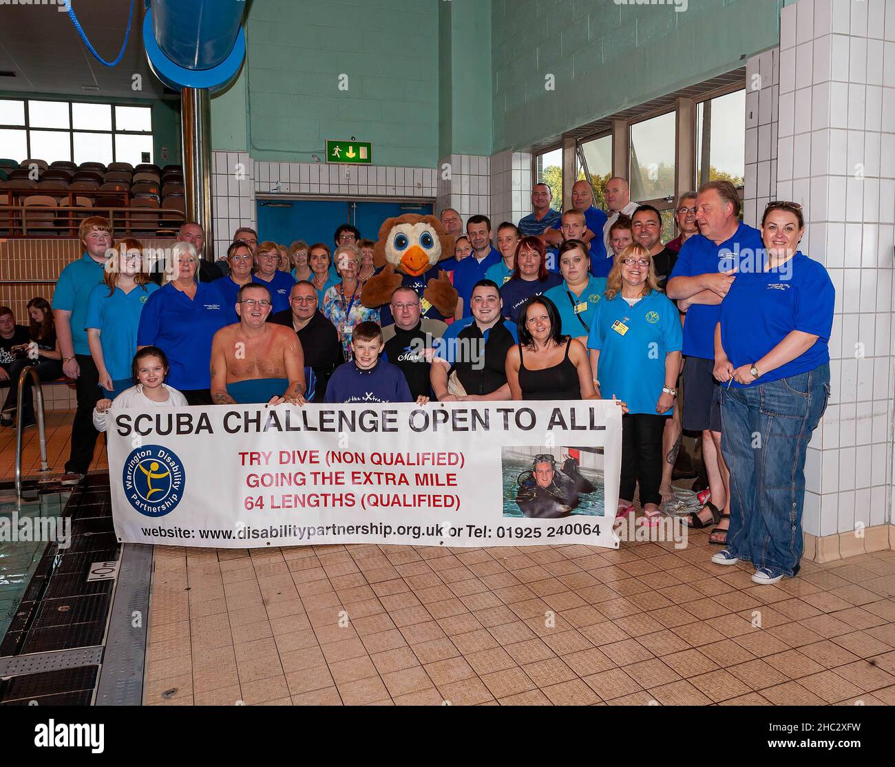 L'équipe de Warrington Disability Partnership pose avec sa bannière après une nage caritative pour « aller plus loin » Banque D'Images