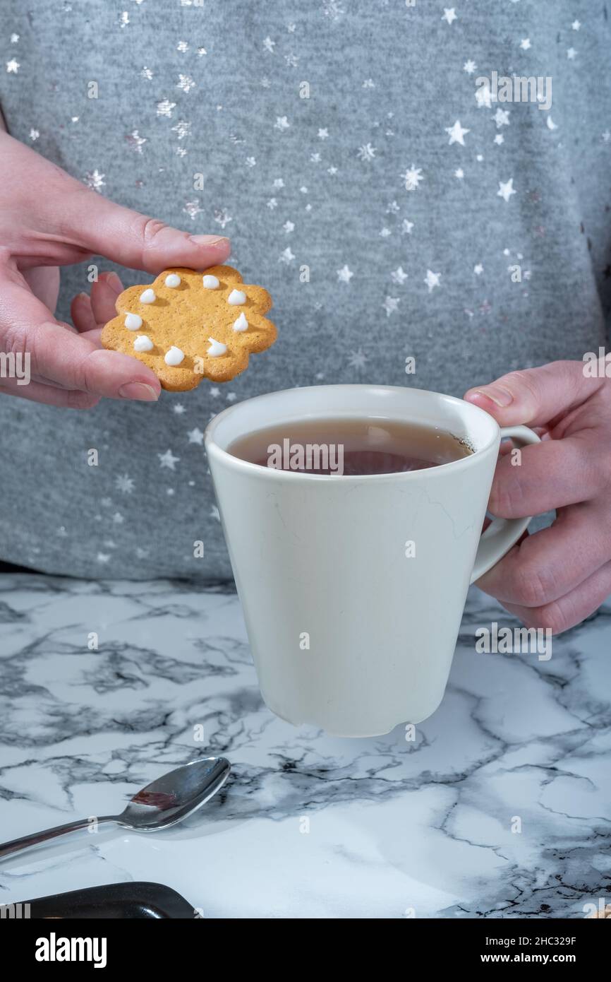 Helsinki / Finlande - 12 DÉCEMBRE 2021 : une femme caucasienne tenant un pain d'épice et une tasse de thé Banque D'Images