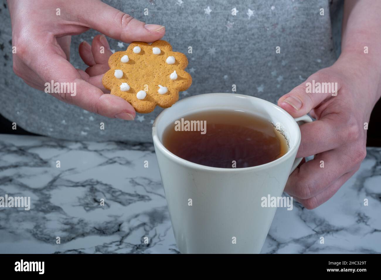 Helsinki / Finlande - 12 DÉCEMBRE 2021 : une femme caucasienne tenant un pain d'épice et une tasse de thé Banque D'Images