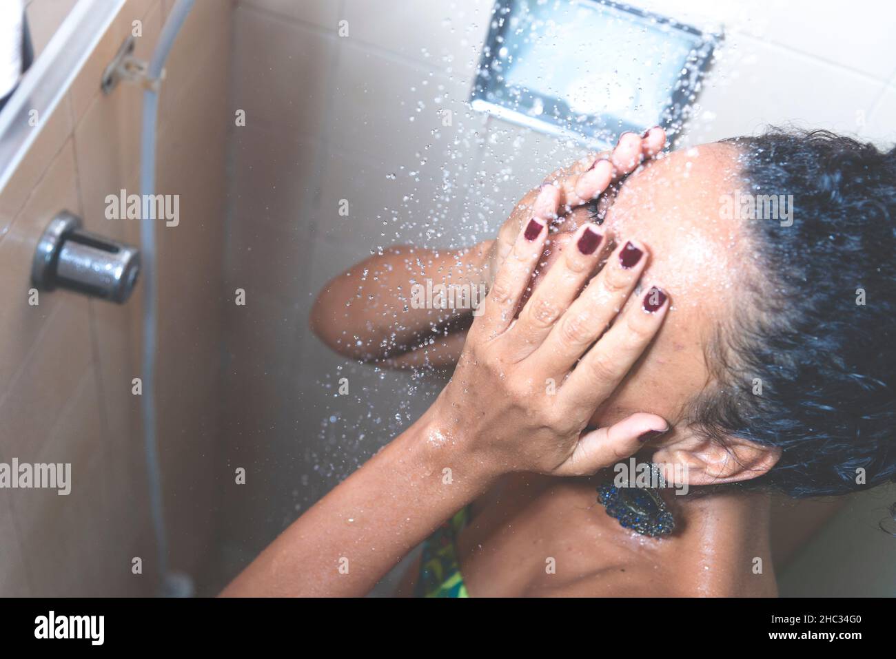 Portrait d'une femme dans la salle de bains se lavant elle-même.Salvador, Bahia, Brésil. Banque D'Images
