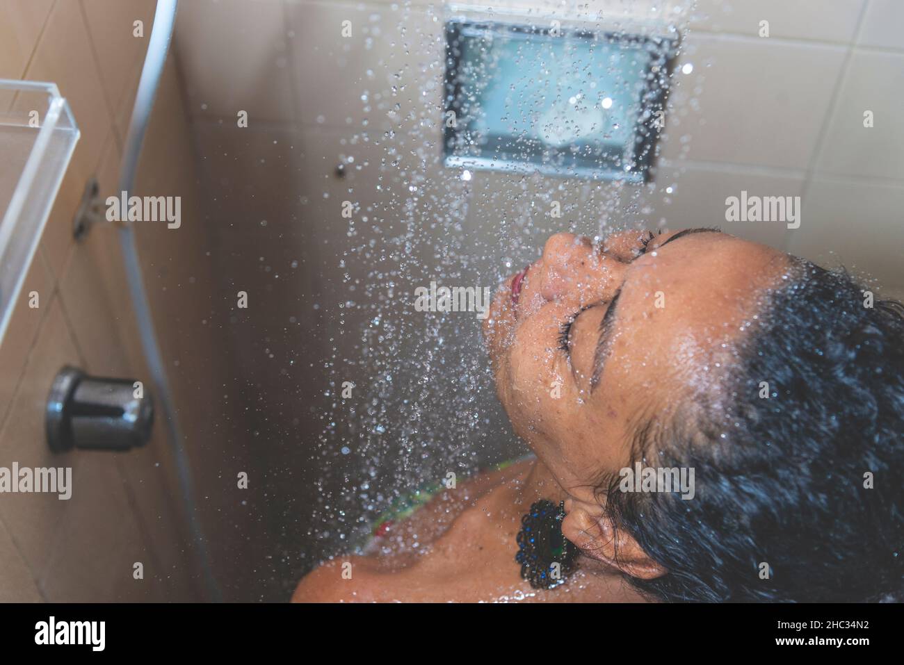 Portrait d'une femme dans la salle de bains se lavant elle-même.Salvador, Bahia, Brésil. Banque D'Images