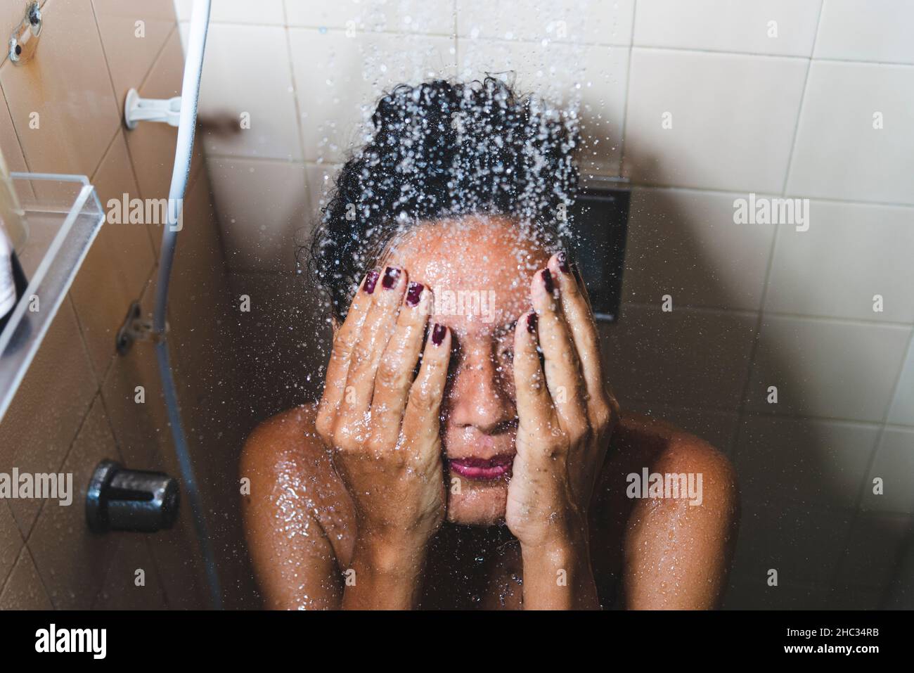 Portrait d'une femme dans la salle de bains se lavant elle-même.Salvador, Bahia, Brésil. Banque D'Images