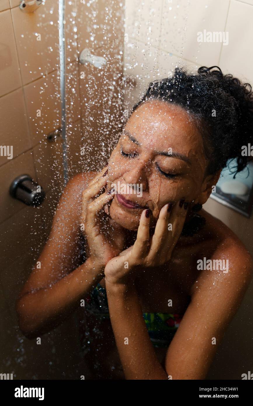 Portrait d'une femme dans la salle de bains se lavant elle-même.Salvador, Bahia, Brésil. Banque D'Images