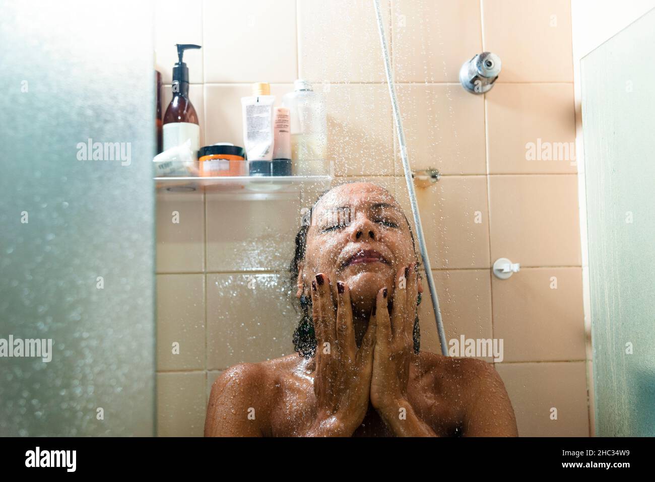 Portrait d'une femme dans la salle de bains se lavant elle-même.Salvador, Bahia, Brésil. Banque D'Images
