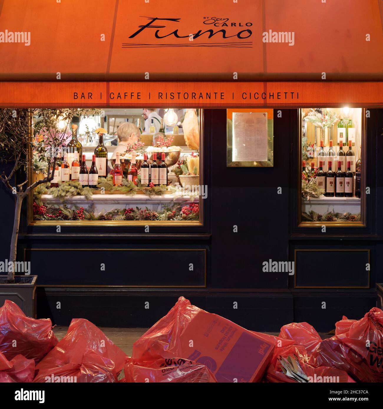 Londres, Grand Londres, Angleterre, décembre 15 2021: Restaurant italien Fumo la nuit avec sacs de déchets en premier plan. Banque D'Images