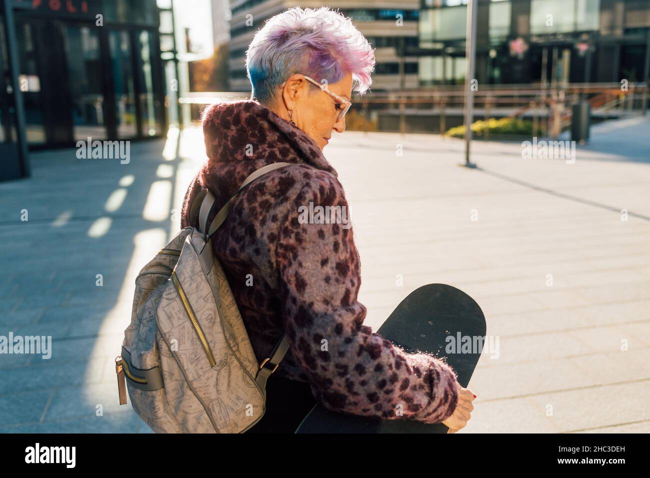 Italie, femme senior à la mode transportant un skateboard en ville Banque D'Images