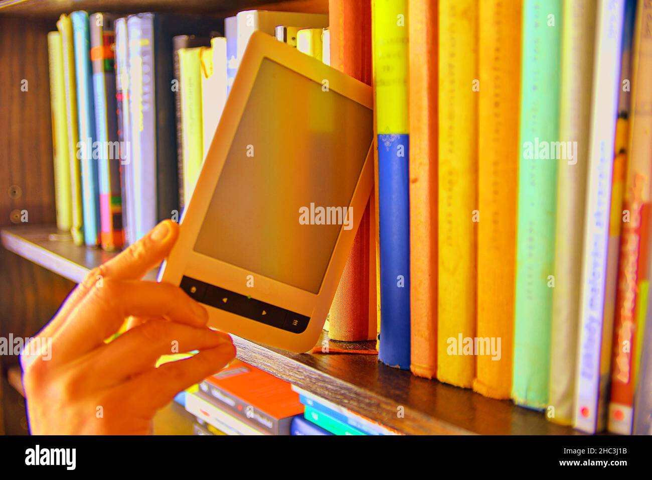 Livre électronique choisi à partir d'une bibliothèque étagère. Le livre électronique sur une étagère parmi les nombreux livres de la bibliothèque. Concept de bibliothèque Booksand Banque D'Images