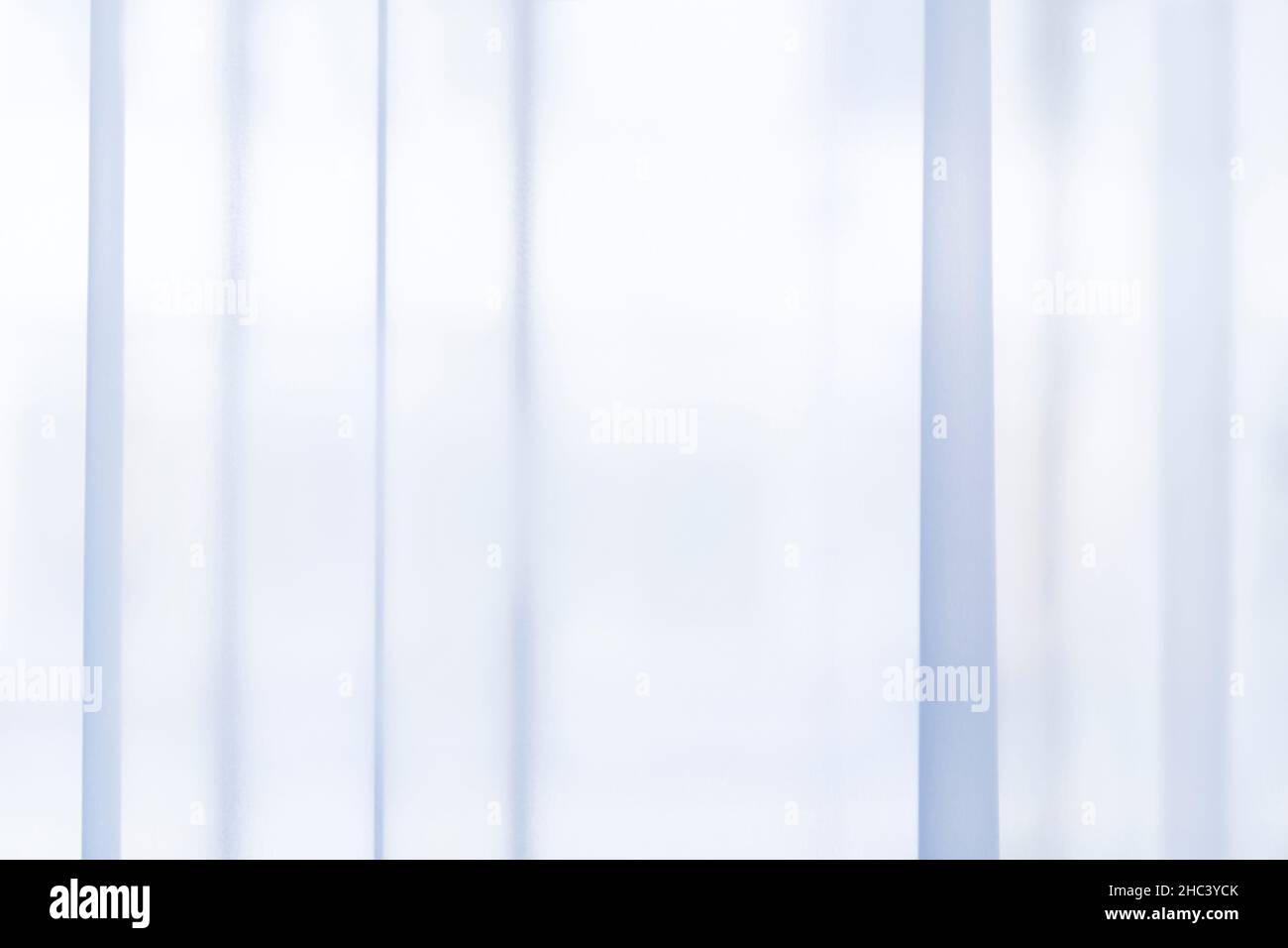 Lumière passant par des rideaux ou des rideaux bleu clair, transparents et plissés.Répétitions linéaires verticales à rayures.Arrière-plan souple abstrait. Banque D'Images