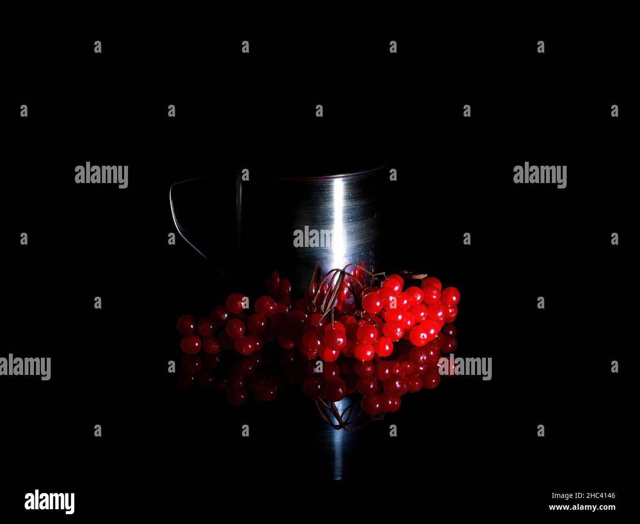 Tasse de thé en métal avec baies de viburnum dans l'obscurité. Banque D'Images