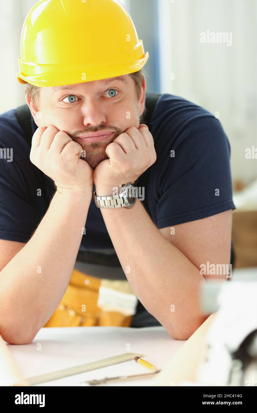 Travailleur portant un casque d'architecte pensant, regardant ennuyé et fatigué sur le chantier de construction Banque D'Images