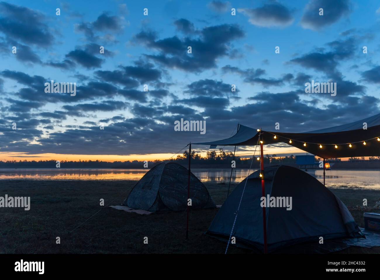 Campez sous la tente au lever du soleil du matin au bord du lac Banque D'Images