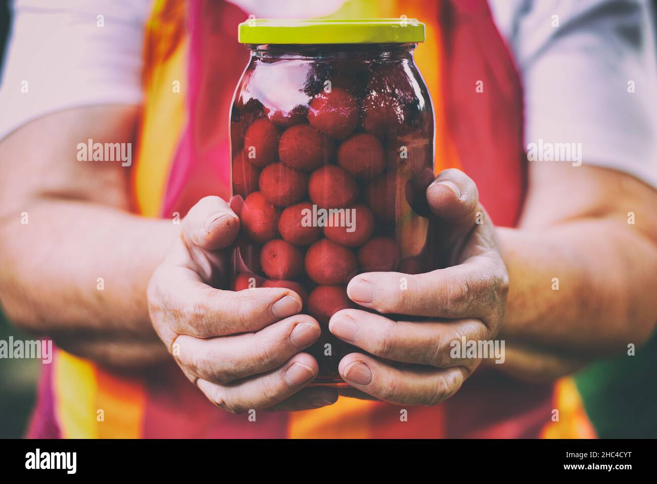 Femme âgée tenant un pot de compote de cerises.Délicieuses cerises en