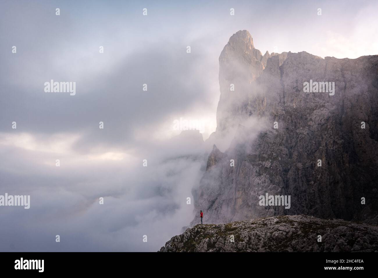 homme debout au bord d'une falaise dans les montagnes de pâle di san martino dans les dolomites entouré de nuages Banque D'Images