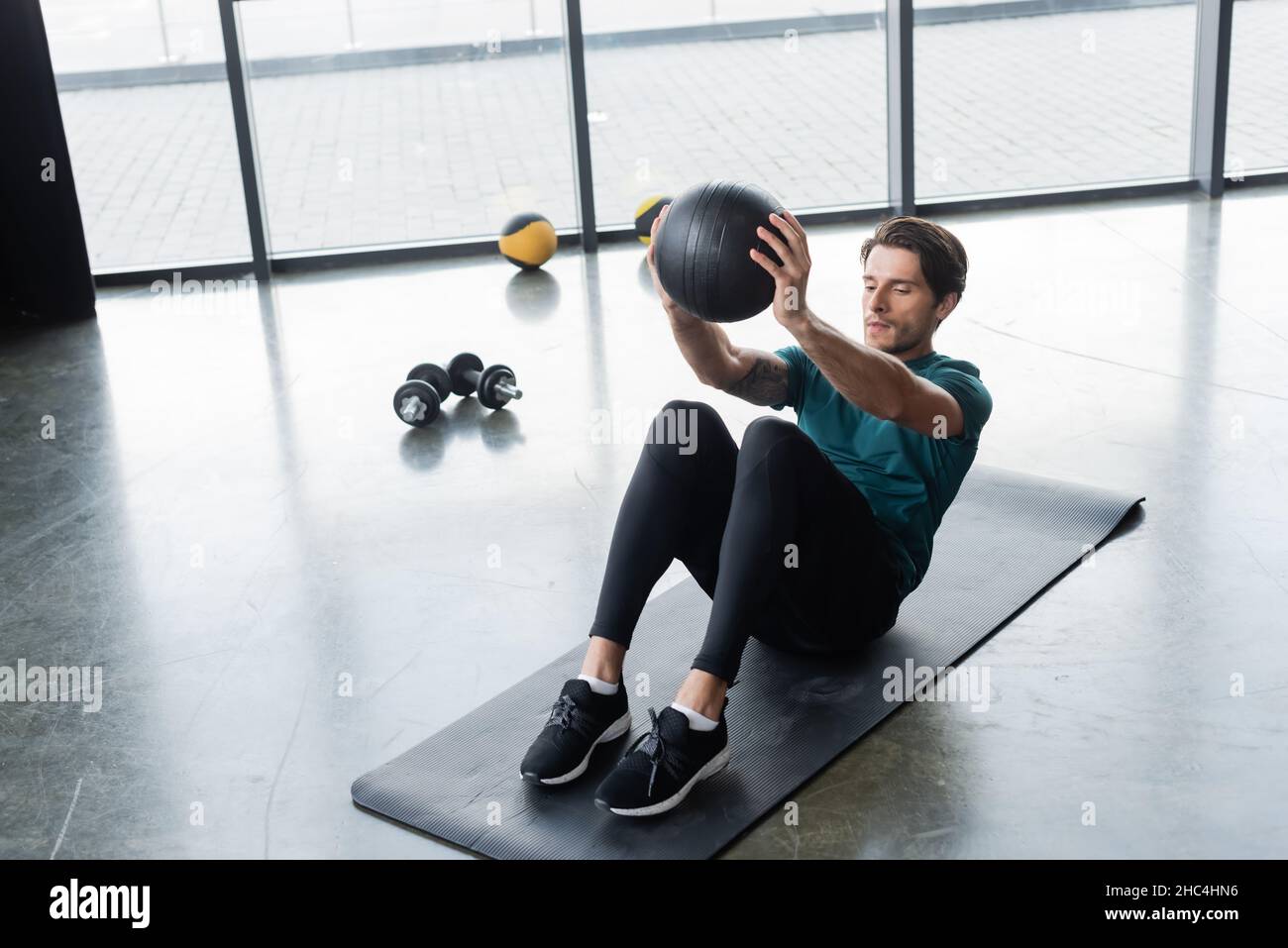 Sportif s'entraîner avec un ballon de slam sur un tapis de fitness dans le centre sportif Banque D'Images