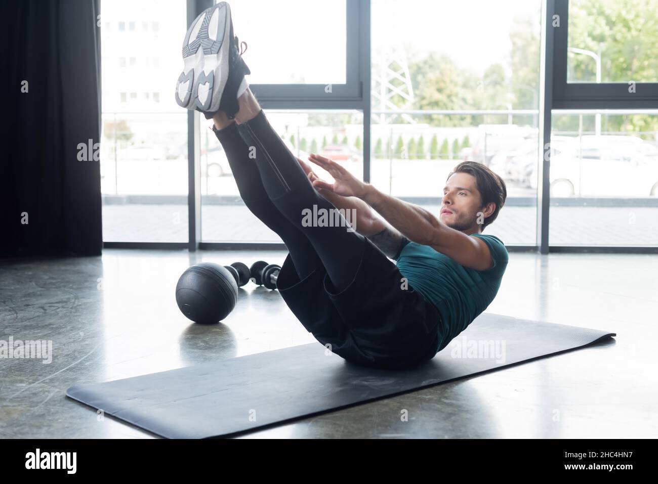 Un sportif s'entraîne sur un tapis de fitness près du slam ball dans la salle de gym Banque D'Images