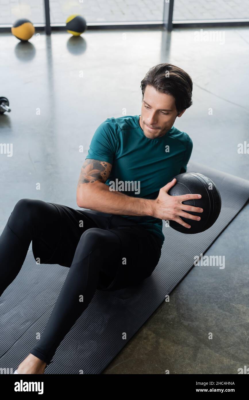Brunette sport s'entraîne avec un ballon de slam sur un tapis de fitness dans le centre sportif Banque D'Images