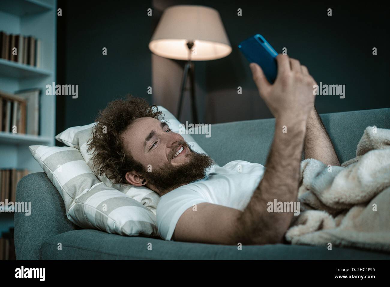 Shapely Guy regarde ses séries préférées sur son téléphone avant d'aller dormir.Il regarde les séries toute la nuit dans son lit.Gros plan.Photo de haute qualité Banque D'Images