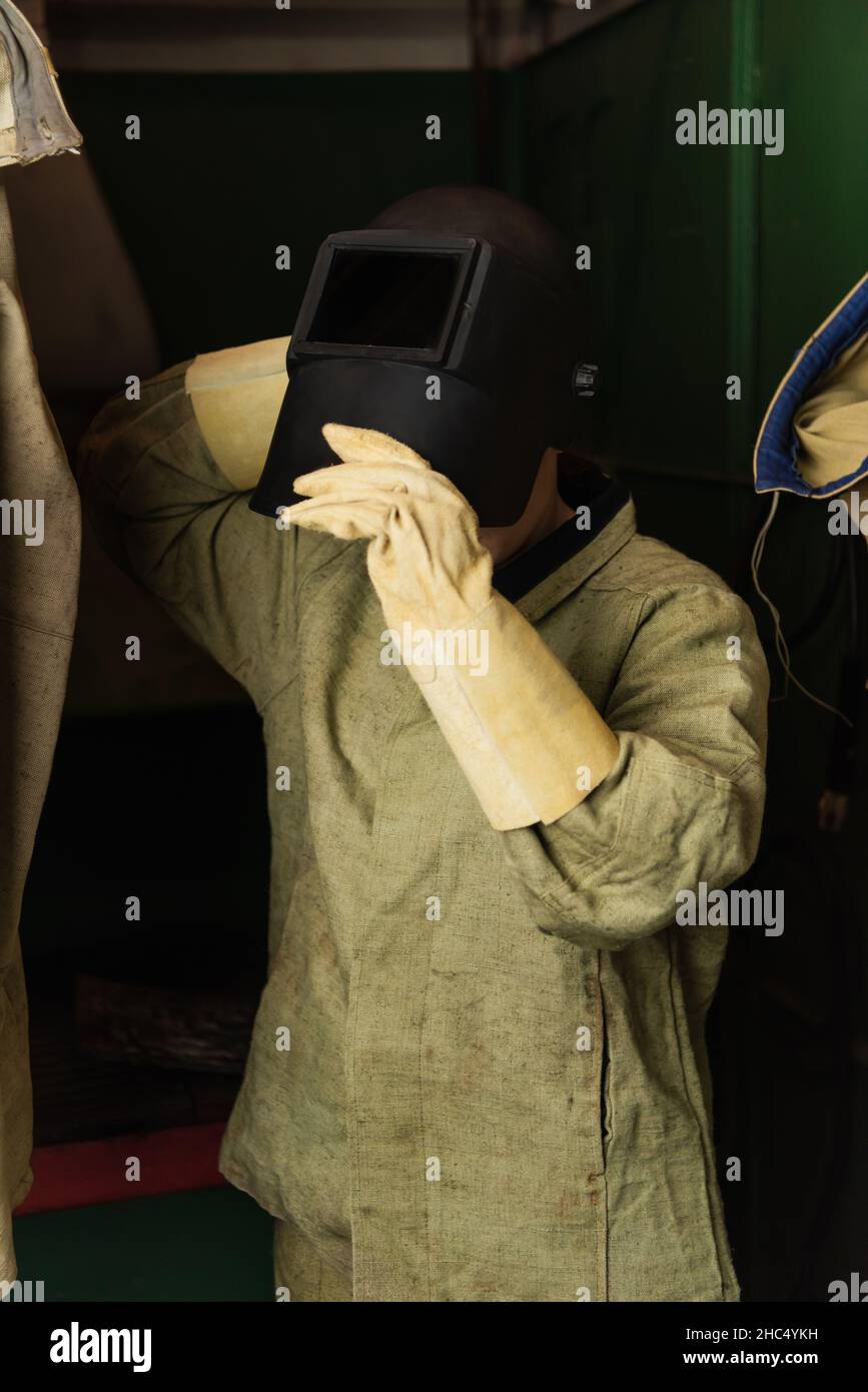 Soudeur avec des gants de protection portant un masque de soudage en usine Banque D'Images