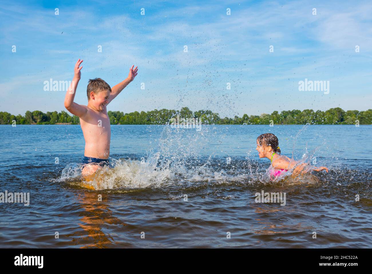 Les enfants heureux jouent et s'amuser dans la rivière lors d'une journée ensoleillée d'été.Concept de vacances. Banque D'Images